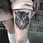 Tiger face tattoo on girl's thigh