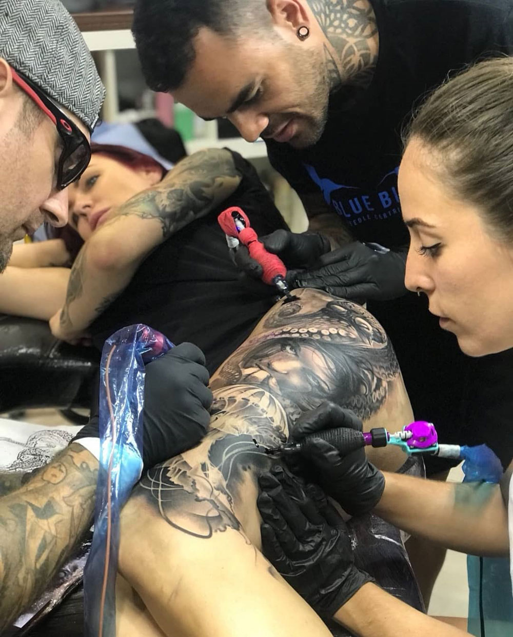 Three tattoo artists working